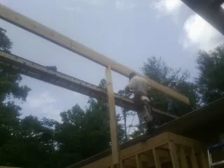 Carpenter setting a ridge beam over a new addition frame — Ice Dam Removal by Roofing Brothers in Walcott