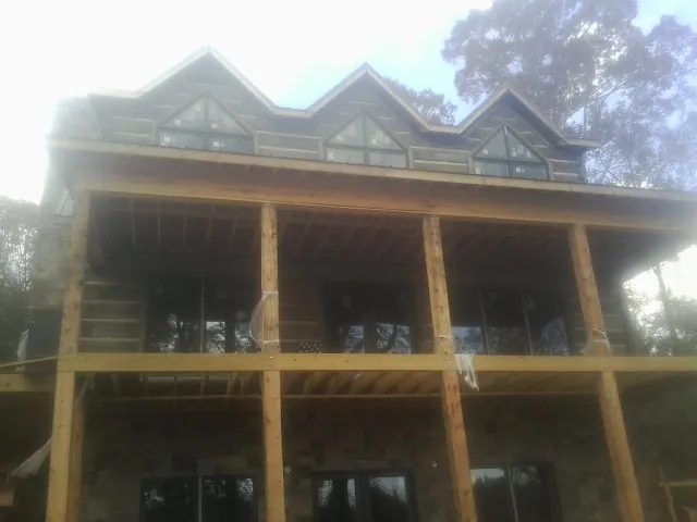 Dormers and porch framing on a large log home under construction — Roof Coating work by our crew in Walcott