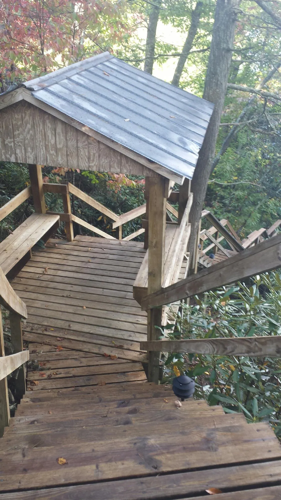 Metal roofed shelter over wooden steps on a wooded walkway — Skylight Repair & Installation work by our crew in Walcott