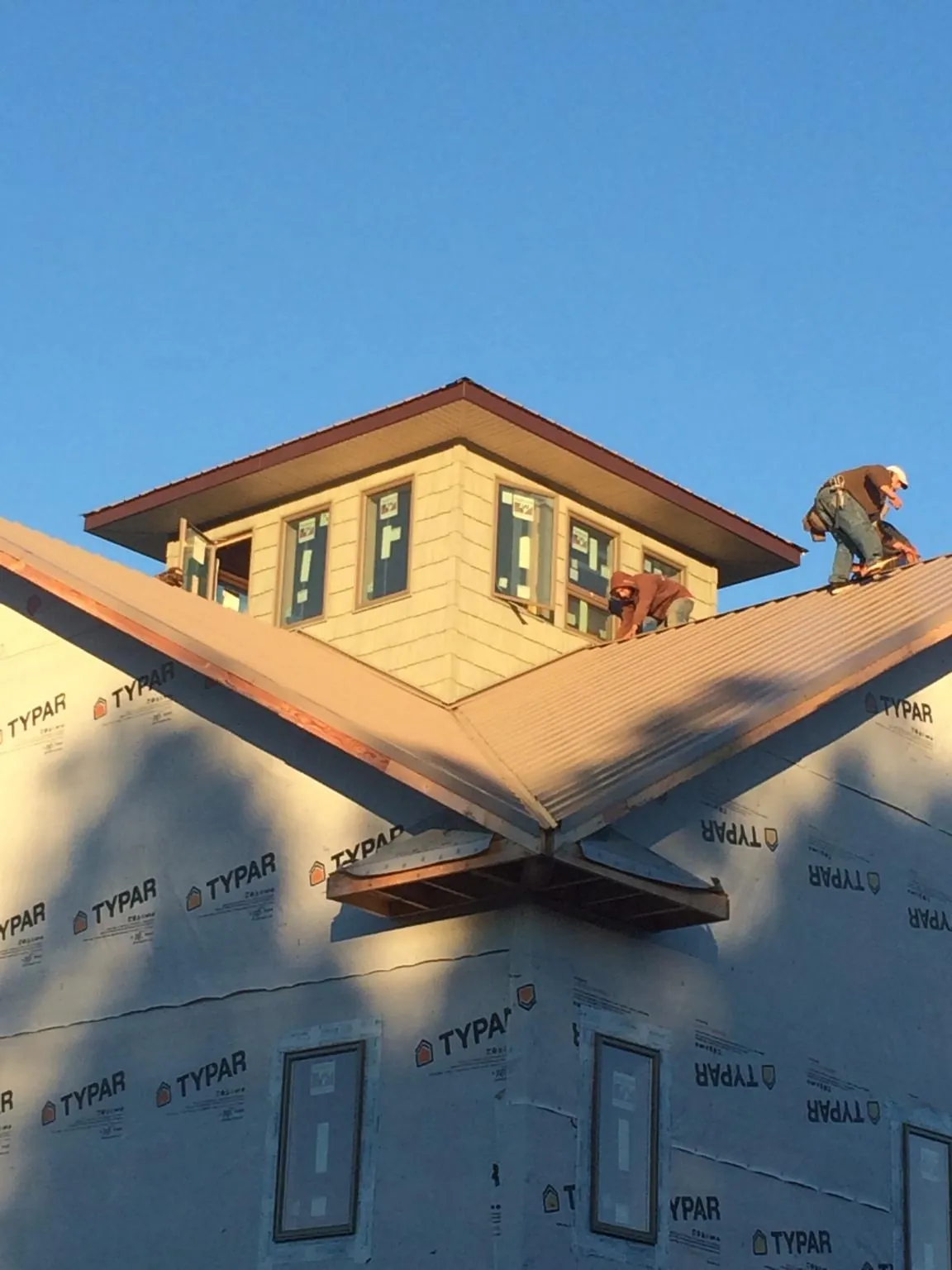 Roofers working around a rooftop cupola on a new metal roof at sunset — Roof Waterproofing in Walcott by Roofing Brothers